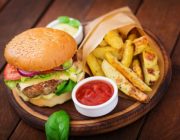 Grande panino - hamburger con succulenti hamburger di manzo, formaggio, pomodoro e cipolla rossa sul tavolo di legno