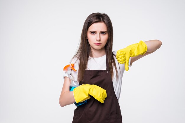 Grande tempo di pulizia. casalinga moderna con guanti di gomma e spugna da cucina e una bottiglia di detersivo che mostra i pollici verso il basso isolati