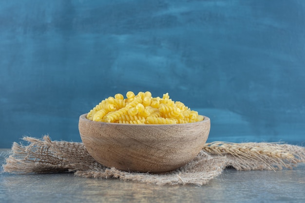 Grano con una ciotola di pasta sull'asciugamano, sulla superficie di marmo.