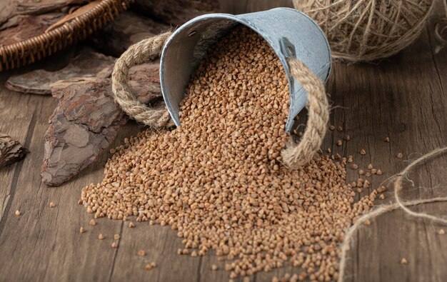 Grano saraceno crudo dal secchio di metallo sulla tavola di legno