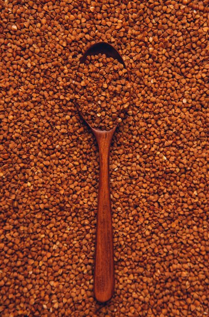 Grano saraceno in un cucchiaio di legno. vista dall'alto, verticale