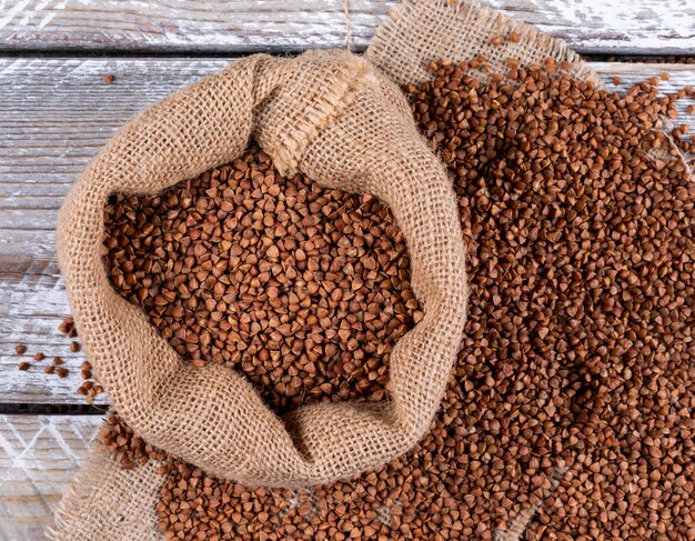Grano saraceno in un sacco su un panno di sacco e legno chiaro. disteso.