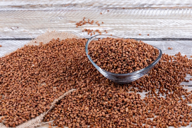 Grano saraceno in una ciotola e accanto. Veduta dall'alto su un legno chiaro