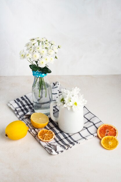 Grappoli di fiori freschi in vaso e brocca vicino frutti