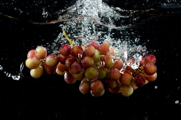 Grappolo d'uva schizzato in acqua in nero