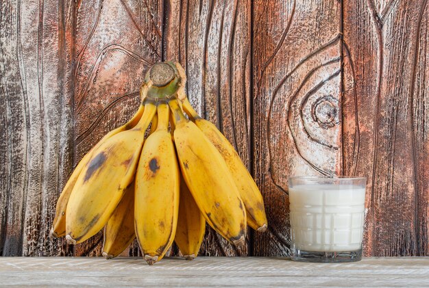 Grappolo di banane con vista laterale del latte su un legno