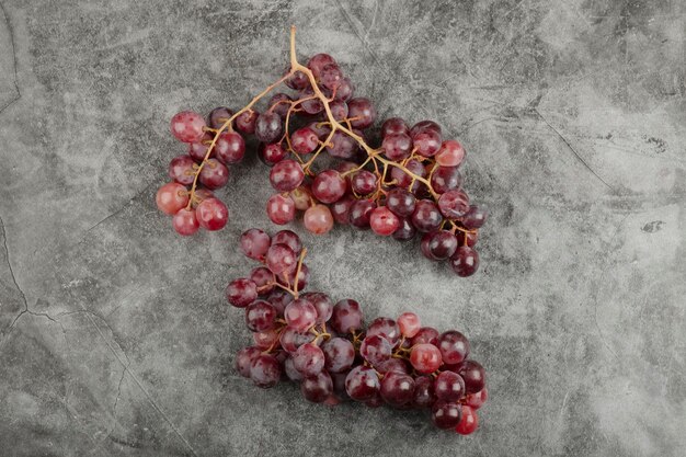 Grappolo di uva matura fresca rossa sulla superficie di marmo.