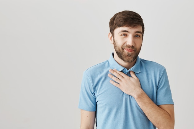 Grato giovane felice sorridente e tenendo la mano sul petto