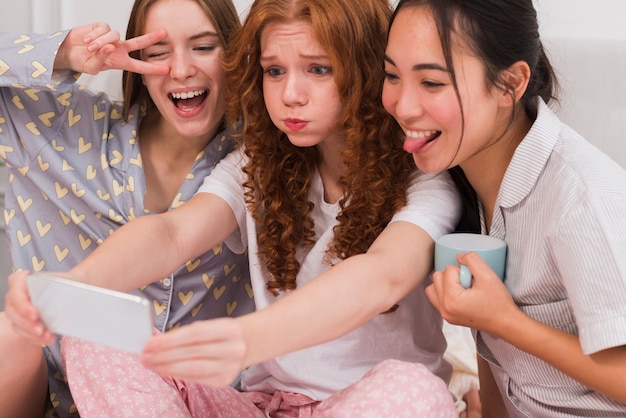 Gruppo allegro di amiche che hanno festa in pigiama