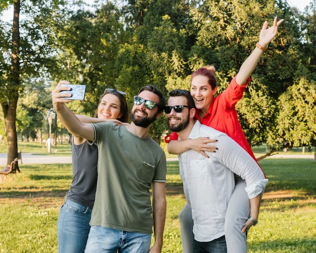 Gruppo di amici adulti allegri che prendono insieme selfie