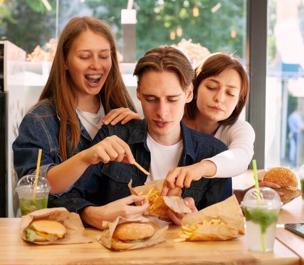 Gruppo di amici al ristorante fast food che mangia hamburger