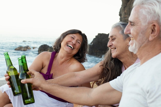 Gruppo di amici anziani che bevono birre sulla spiaggia