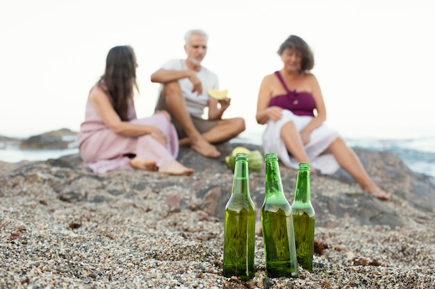 Gruppo di amici anziani che bevono birre sulla spiaggia