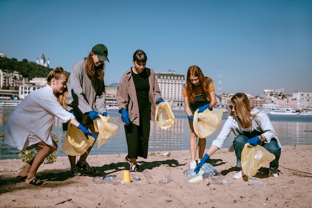 Gruppo di amici attivisti che raccolgono rifiuti di plastica sulla spiaggia. Conservazione dell'ambiente.