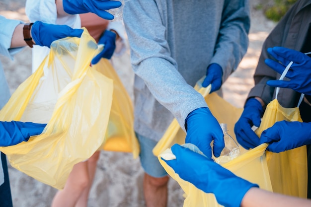 Gruppo di amici attivisti che raccolgono rifiuti di plastica sulla spiaggia. Conservazione dell'ambiente.