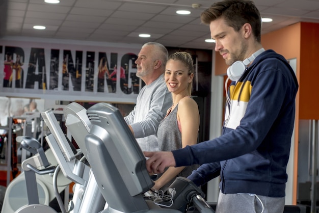 Gruppo di amici caucasici che si esercitano insieme su tapis roulant in palestra