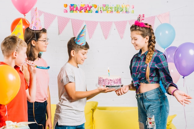 Gruppo di amici che celebrano il compleanno della ragazza con torta a casa