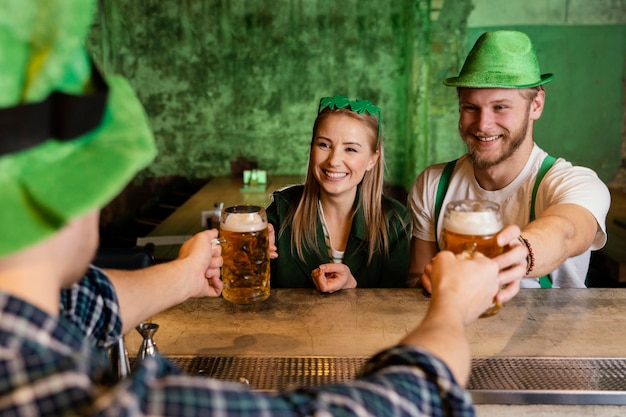 Gruppo di amici che festeggiano st. patrick's day con drink al bar