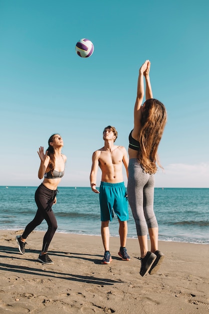 Gruppo di amici che giocano a pallavolo in spiaggia