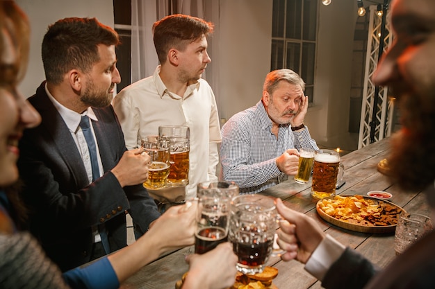 Gruppo di amici che godono di drink serali con birra sulla tavola di legno