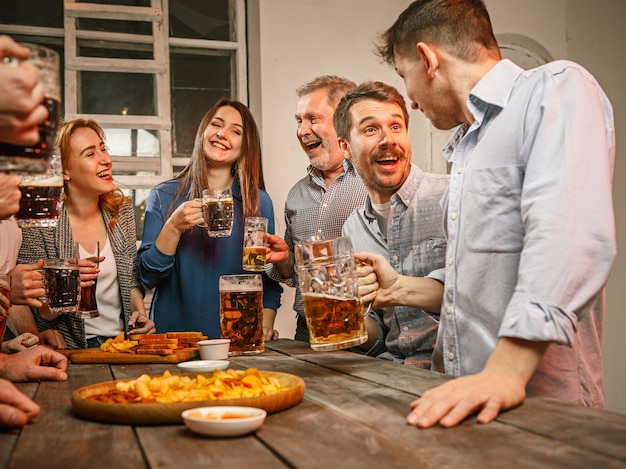 Gruppo di amici che godono di drink serali con birra sulla tavola di legno