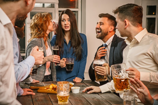 Gruppo di amici che godono di drink serali con birra sulla tavola di legno