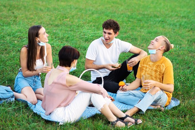 Gruppo di amici che mangiano e bevono, divertendosi a un picnic