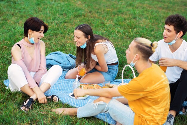 Gruppo di amici che mangiano e bevono, divertendosi a un picnic