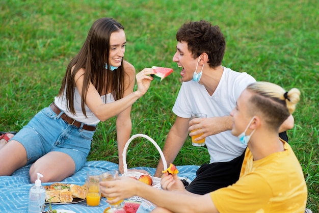 Gruppo di amici che mangiano e bevono, divertendosi a un picnic