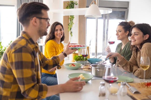 Gruppo di amici che mangiano pasta insieme in cucina