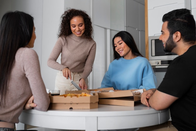 Gruppo di amici che mangiano pizza a casa insieme