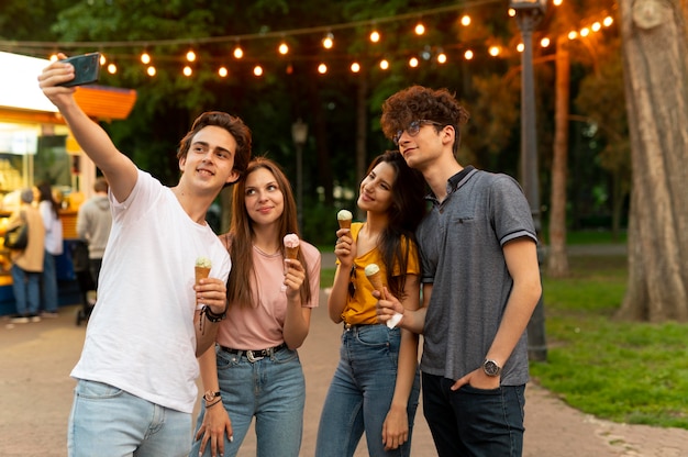 Gruppo di amici che mangiano un gelato all'aperto e si fanno selfie