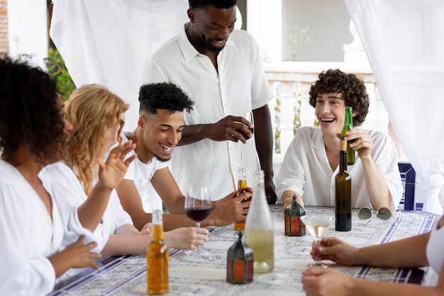 Gruppo di amici che si divertono durante una festa bianca con bevande