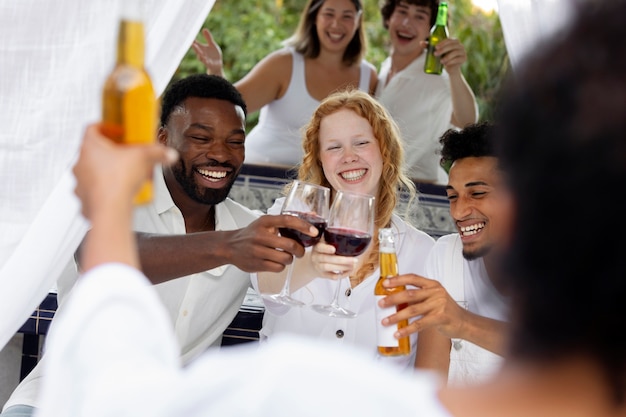 Gruppo di amici che si divertono durante una festa bianca con bevande