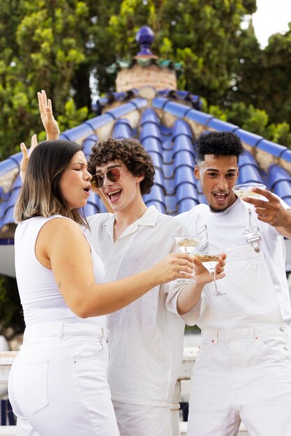 Gruppo di amici che si divertono durante una festa bianca con bevande