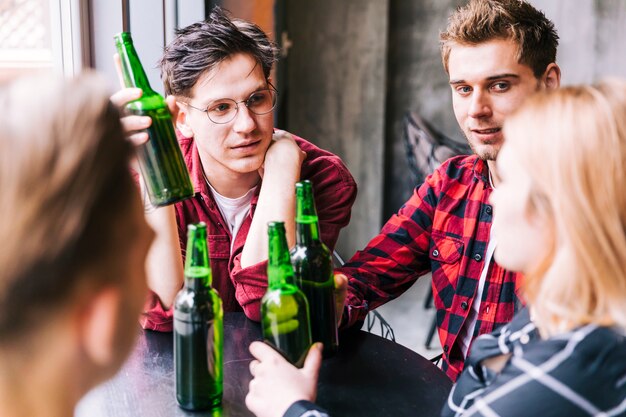 Gruppo di amici che si siedono insieme tenendo bottiglie di birra verde