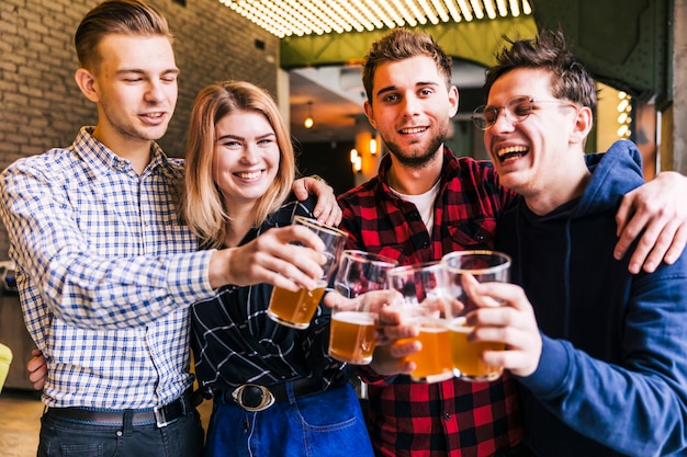 Gruppo di amici che tintinnano i bicchieri di birra nel pub