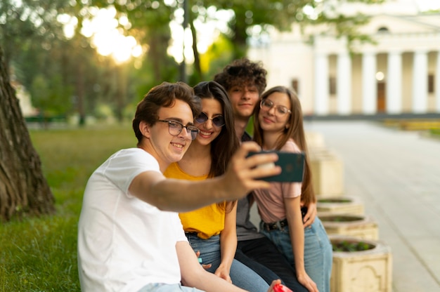 Gruppo di amici che trascorrono del tempo insieme all'aperto nel parco e si fanno selfie