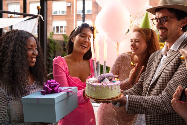 Gruppo di amici con la torta a una festa di compleanno a sorpresa