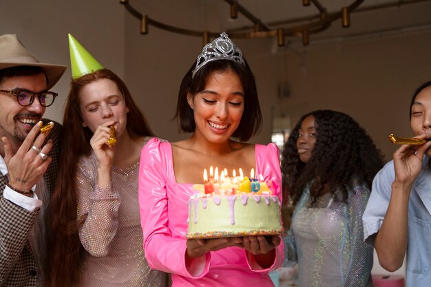 Gruppo di amici con torta a una festa di compleanno a sorpresa