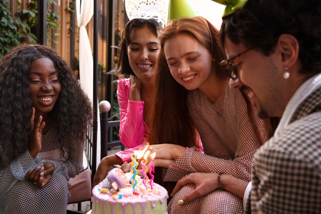 Gruppo di amici con torta a una festa di compleanno a sorpresa