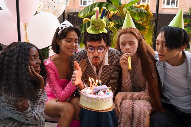 Gruppo di amici con torta a una festa di compleanno a sorpresa