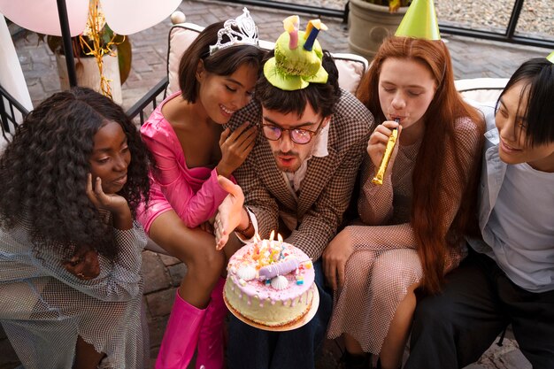 Gruppo di amici con torta a una festa di compleanno a sorpresa