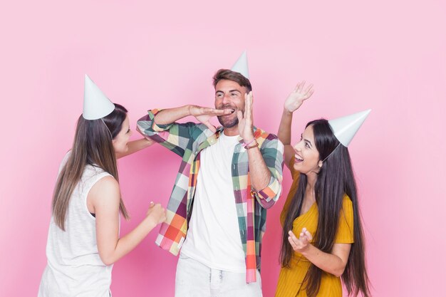 Gruppo di amici felici che celebrano su sfondo rosa