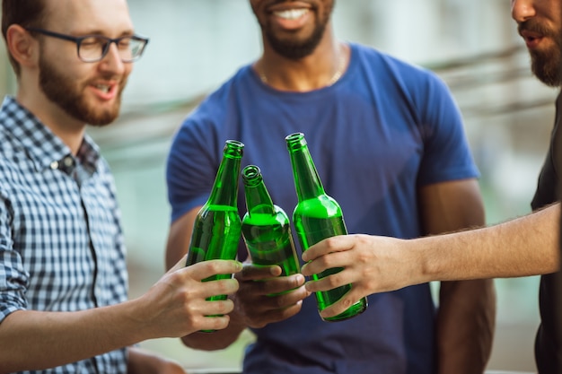 Gruppo di amici felici che hanno festa della birra nel giorno di estate. Riposare insieme all'aperto, festeggiare e rilassarsi, ridere. Stile di vita estivo, concetto di amicizia.