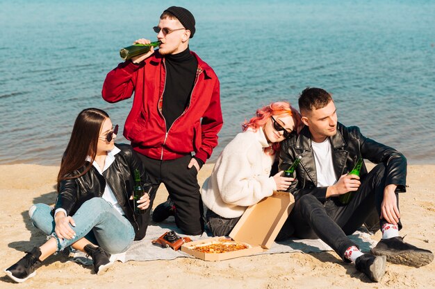 Gruppo di amici felici che hanno festa in spiaggia