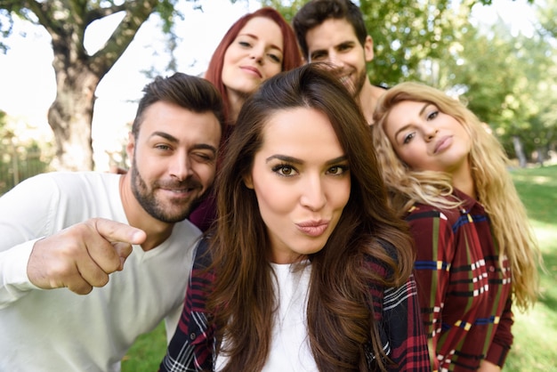 Gruppo di amici in un selfie con una ragazza in mezzo mettere bacio faccia