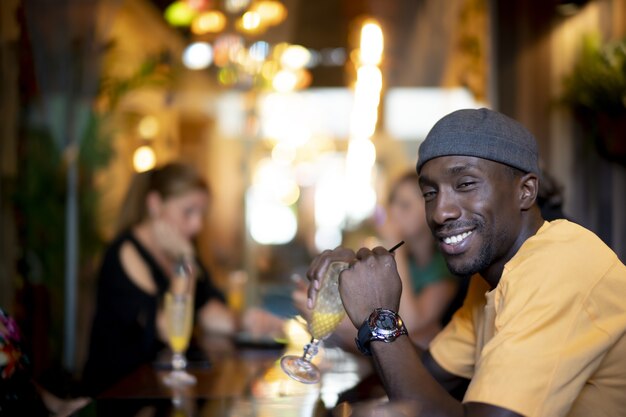 Gruppo di amici multietnici che bevono cocktail e si divertono in un bar