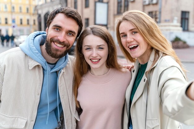 Gruppo di amici smiley all'aperto in città prendendo selfie insieme