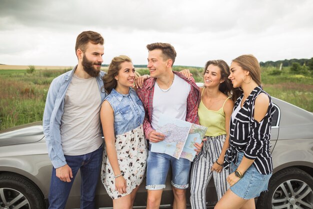 Gruppo di amici sorridenti che fanno una pausa l&#39;automobile che se lo esamina